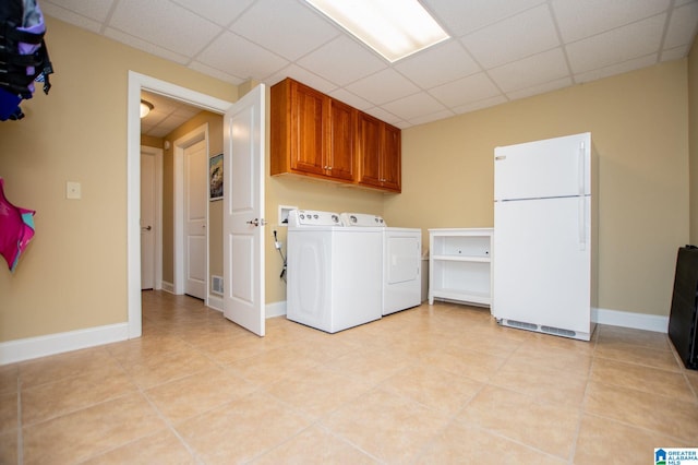 laundry area featuring cabinet space, separate washer and dryer, light tile patterned flooring, and baseboards