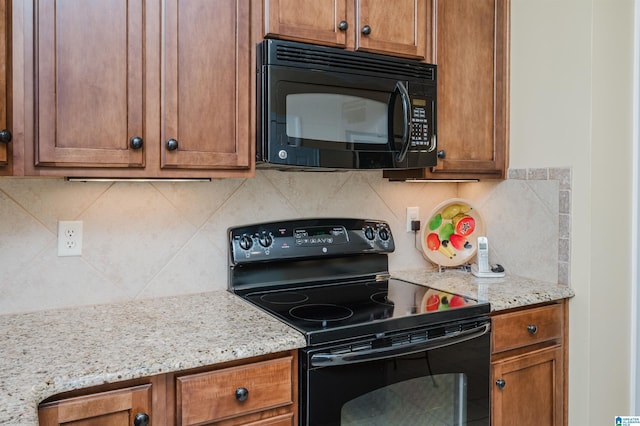 kitchen with black appliances, brown cabinets, decorative backsplash, and light stone counters