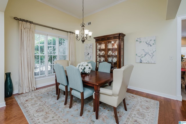 dining area featuring a chandelier, baseboards, ornamental molding, and wood finished floors