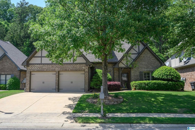 tudor-style house featuring a garage, a front yard, driveway, and brick siding