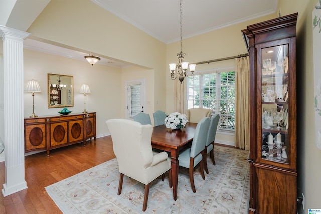 dining area featuring a chandelier, crown molding, ornate columns, and light wood-style flooring