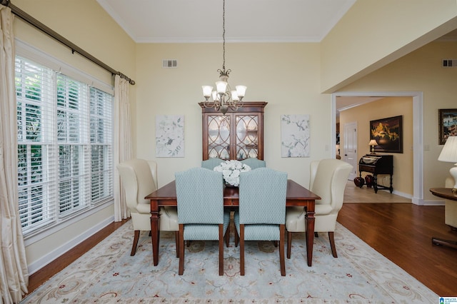 dining area featuring a chandelier, wood finished floors, baseboards, and ornamental molding
