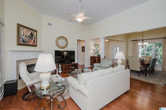 living area featuring ornamental molding, a chandelier, wood finished floors, decorative columns, and a ceiling fan