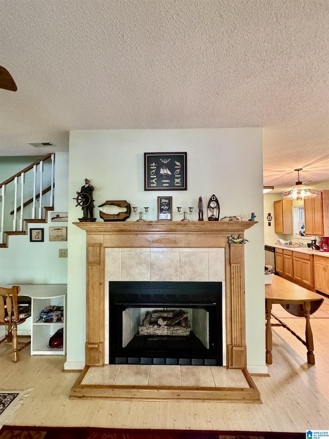 detailed view of wood finished floors, a fireplace, a textured ceiling, and baseboards