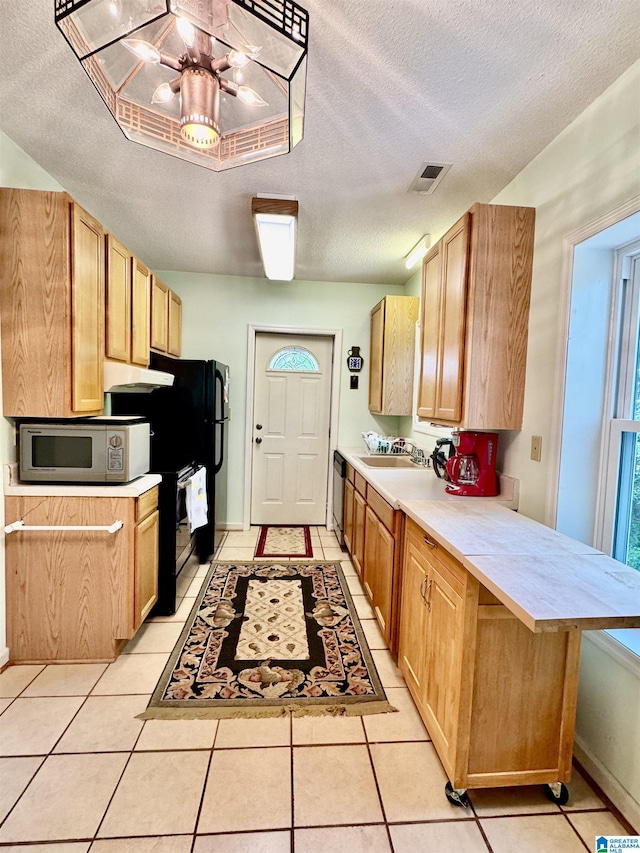 kitchen featuring white microwave, a peninsula, light countertops, a sink, and stainless steel dishwasher