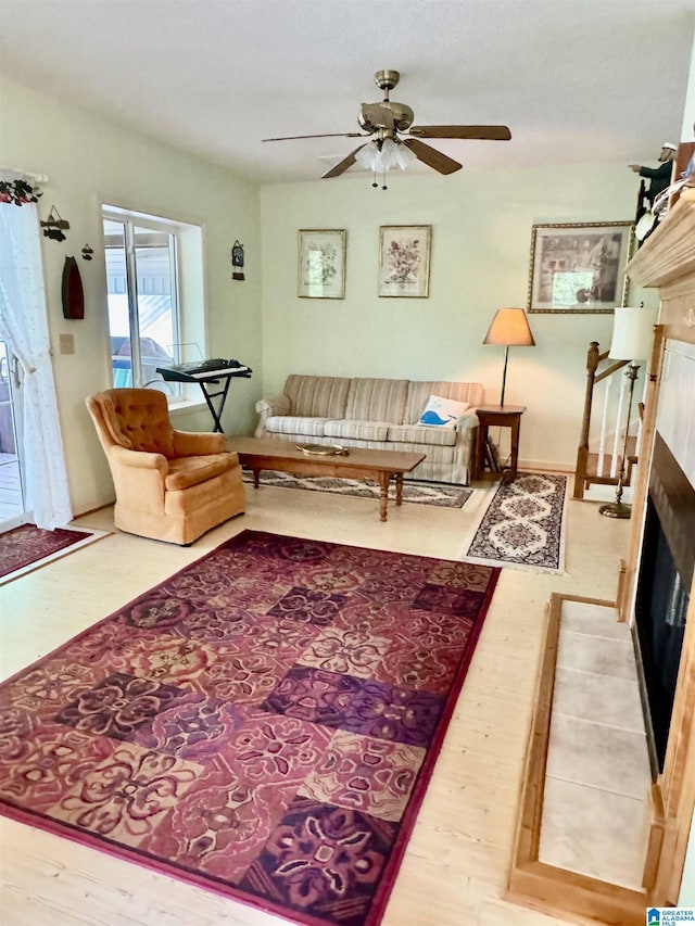 living area featuring a fireplace, wood finished floors, and ceiling fan