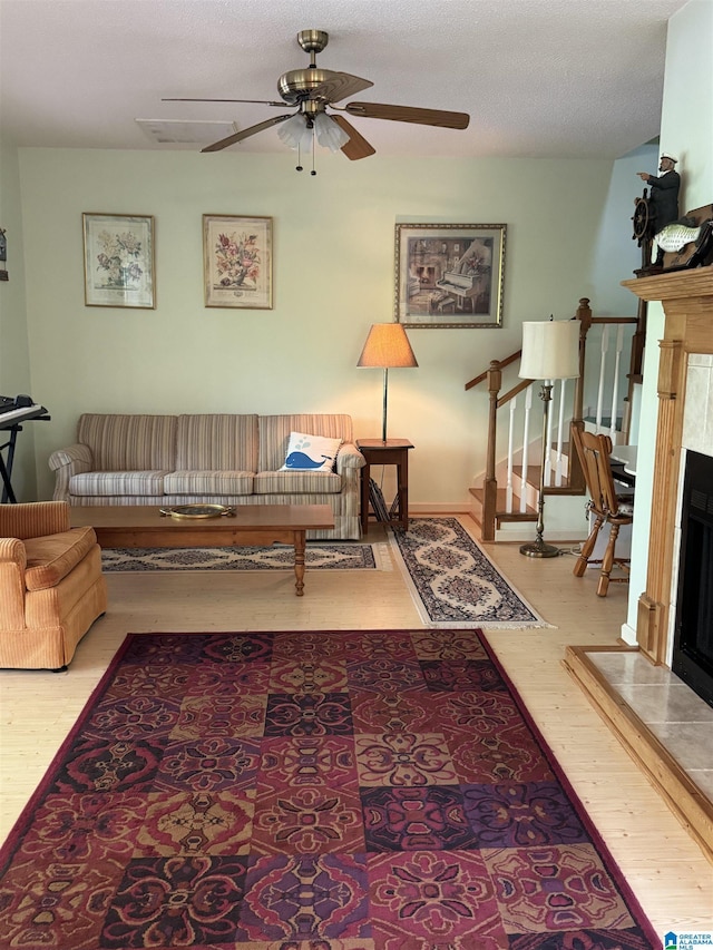 living room featuring ceiling fan, a high end fireplace, wood finished floors, and stairs