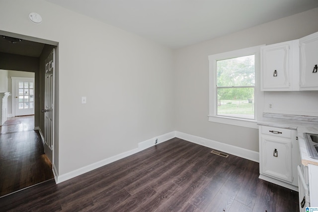 unfurnished dining area with baseboards and dark wood-style flooring
