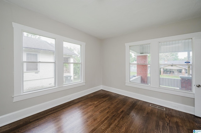 unfurnished room featuring dark wood-style flooring and baseboards