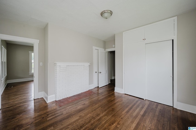 unfurnished bedroom featuring dark wood-style floors, a closet, and baseboards