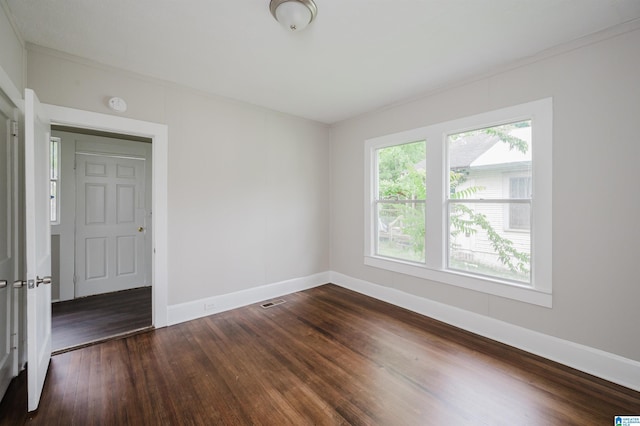unfurnished room featuring baseboards, dark wood-style flooring, and crown molding