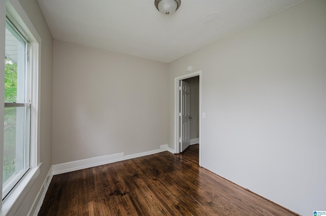 spare room with dark wood-type flooring and baseboards