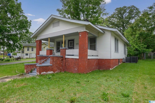 bungalow with a front lawn, covered porch, and cooling unit