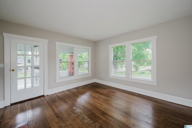 empty room featuring baseboards and dark wood finished floors