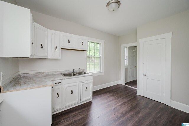 kitchen featuring a sink, dark wood finished floors, white cabinets, light countertops, and baseboards