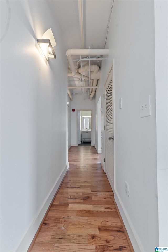 hallway featuring light wood-style flooring and baseboards