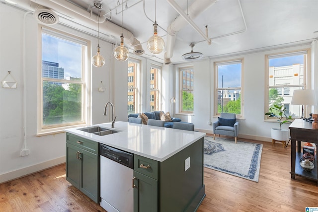 kitchen featuring green cabinets, dishwashing machine, a sink, light wood-style floors, and baseboards