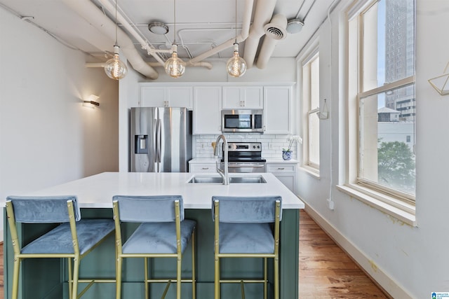 kitchen with appliances with stainless steel finishes, a sink, tasteful backsplash, and white cabinetry