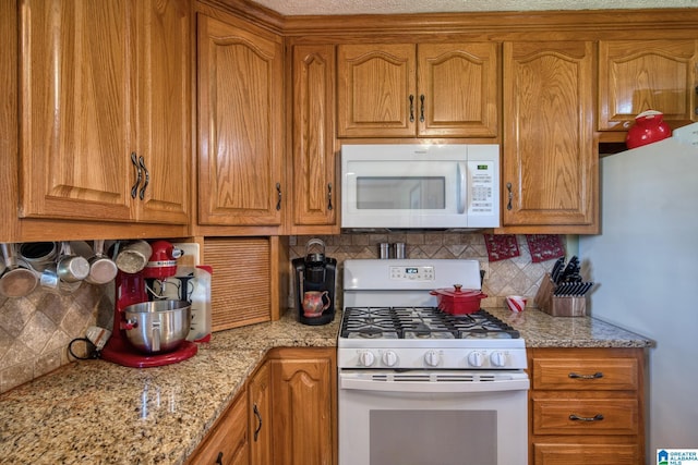 179 Idlewood Cir, Alexandria, AL 36250 - kitchen featuring white appliances, decorative backsplash, brown cabinetry, and light stone counters