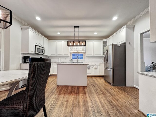 1851 Russet Woods Ln, Hoover, AL 35244 - kitchen featuring appliances with stainless steel finishes, crown molding, light wood-type flooring, white cabinets, and a center island
