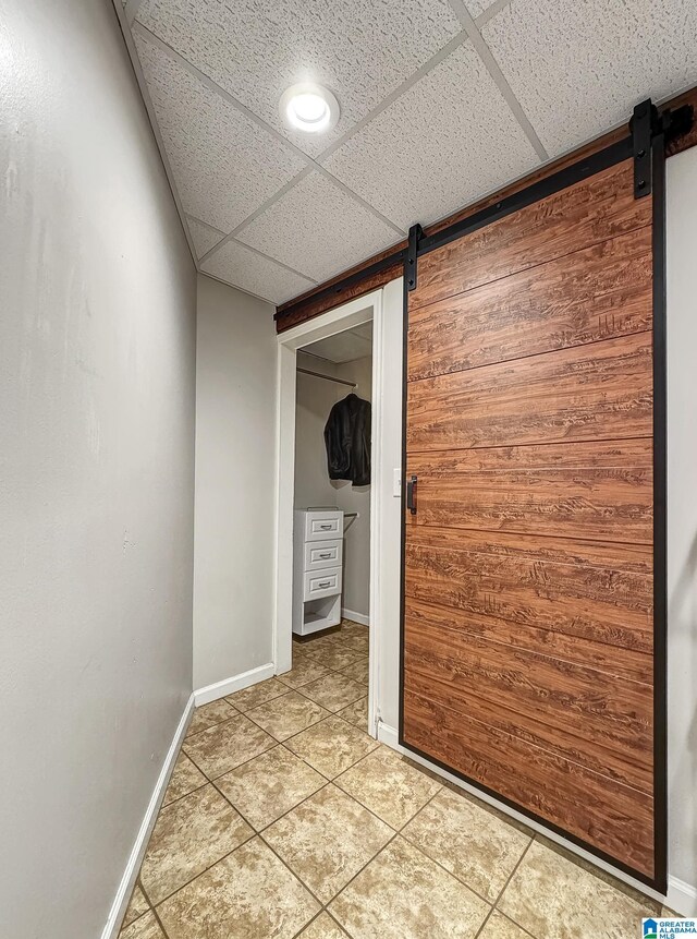 1851 Russet Woods Ln, Hoover, AL 35244 - spare room with a barn door, a drop ceiling, light tile patterned floors, and baseboards
