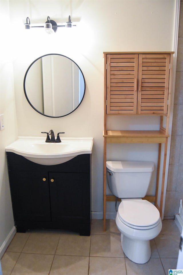 bathroom with toilet, vanity, and tile patterned floors