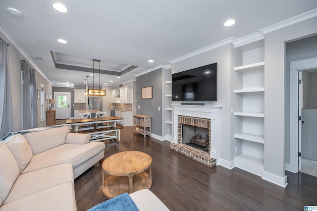 3951 Crest Lndg, Irondale, AL 35210 - living room featuring crown molding, dark wood-style flooring, built in features, a brick fireplace, and baseboards