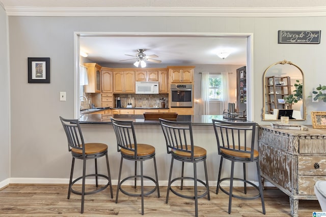 14 Shades Crest Rd, Hoover, AL 35226 - kitchen featuring oven, white microwave, a peninsula, light wood-style floors, and dark countertops