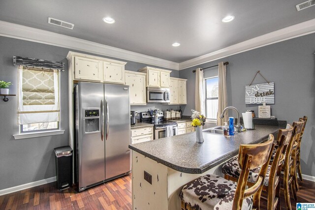 624 Enclave Ln, Calera, AL 35040 - kitchen with stainless steel appliances, a sink, a breakfast bar, dark countertops, and a peninsula