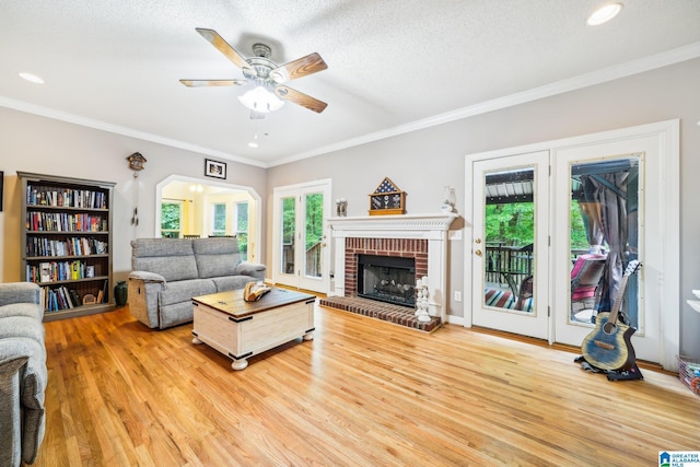 8526 Scenic Ridge Dr, Pinson, AL 35126 - living area with light wood-style flooring, ceiling fan, a fireplace, crown molding, and a textured ceiling