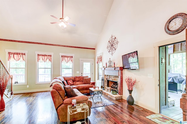 living room with plenty of natural light, stairs, wood finished floors, and high vaulted ceiling