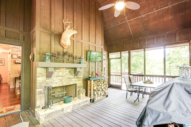 sunroom / solarium with lofted ceiling, ceiling fan, and a stone fireplace