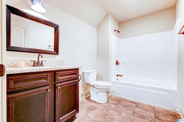 bathroom with baseboards, toilet, vanity, washtub / shower combination, and stone finish flooring