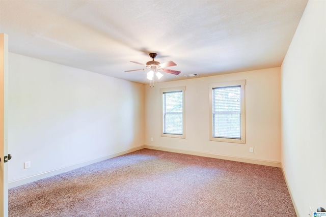 carpeted empty room featuring ceiling fan and baseboards