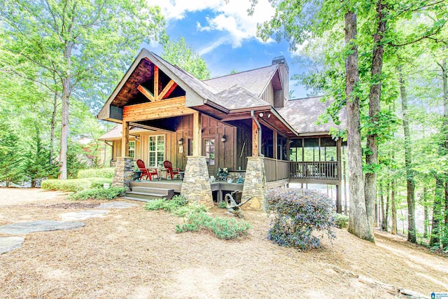 craftsman house with board and batten siding, a chimney, roof with shingles, and a porch