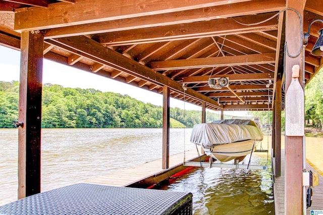 dock area featuring boat lift, a water view, and a wooded view