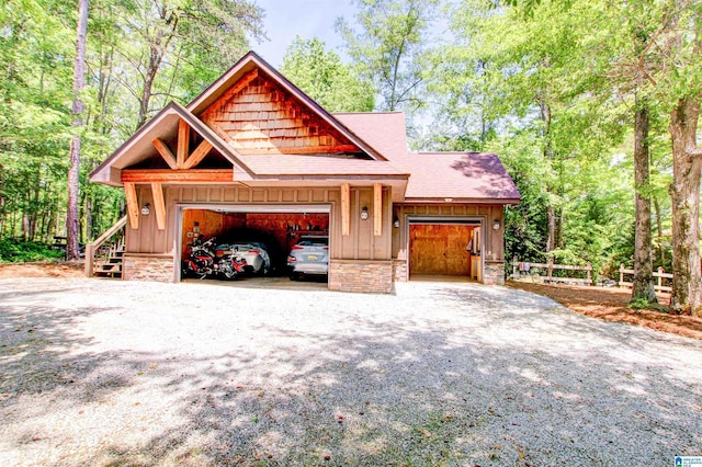 view of front facade with board and batten siding, a shingled roof, a garage, driveway, and stone siding