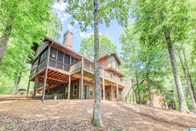 rear view of property featuring a deck, a chimney, and a sunroom