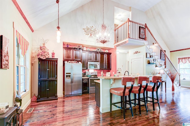 kitchen featuring appliances with stainless steel finishes, dark wood finished floors, a kitchen bar, high vaulted ceiling, and a chandelier