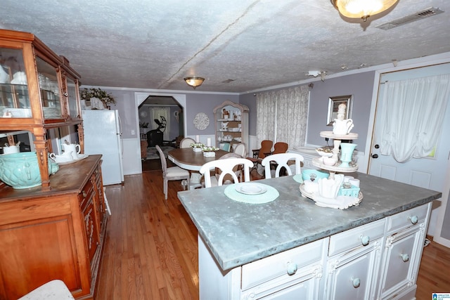 1619 Websters Chapel Rd, Wellington, AL 36279 - kitchen with freestanding refrigerator, arched walkways, wood finished floors, glass insert cabinets, and white cabinetry