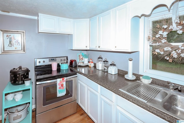 1619 Websters Chapel Rd, Wellington, AL 36279 - kitchen with stainless steel electric range, white cabinetry, a sink, dark countertops, and light wood-style flooring