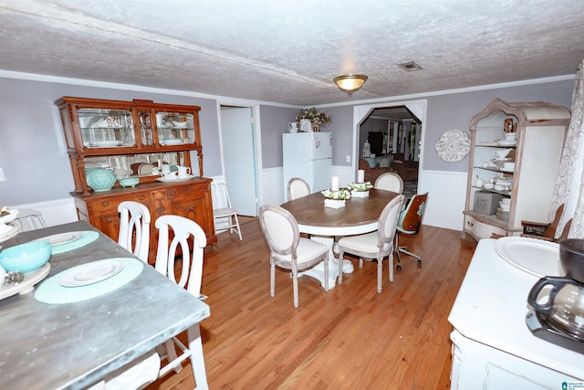 1619 Websters Chapel Rd, Wellington, AL 36279 - dining area featuring wainscoting, light wood-style flooring, a textured ceiling, and arched walkways