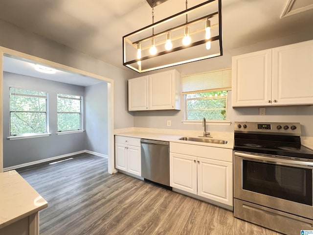 kitchen featuring stainless steel appliances, a sink, light wood-style floors, and white cabinetry
