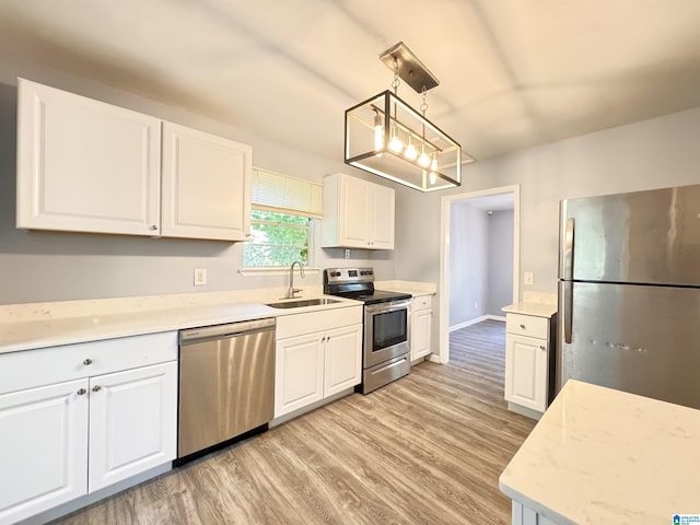 kitchen with stainless steel appliances, a sink, light wood finished floors, and white cabinets
