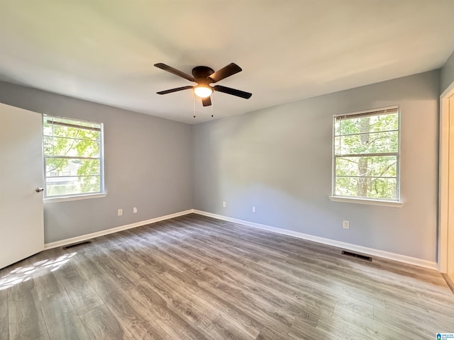 spare room featuring wood finished floors, a ceiling fan, and baseboards