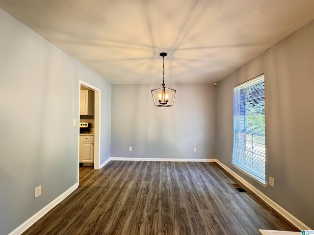 unfurnished dining area featuring dark wood-style floors, baseboards, and a chandelier