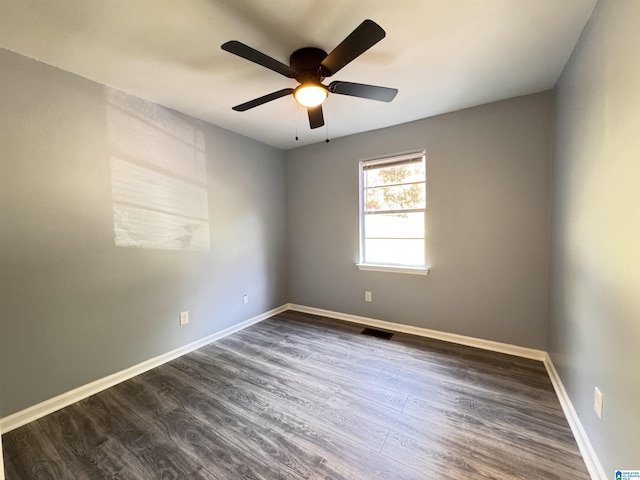 spare room with dark wood-style flooring, a ceiling fan, and baseboards