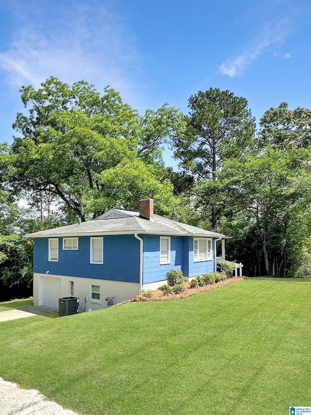 view of front facade with a chimney, a garage, a front yard, and driveway