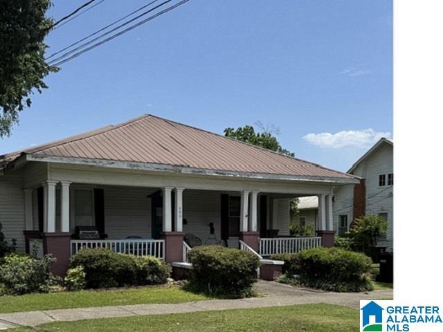 406 6th St N, Clanton, AL 35045 - view of front of house featuring covered porch, metal roof, and a front lawn