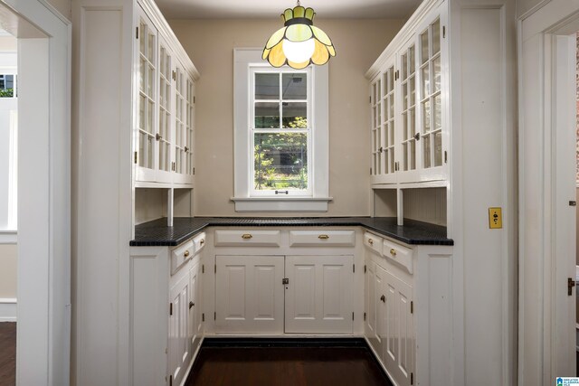 1479 Milner Cres S, Birmingham, AL 35205 - kitchen with dark countertops, glass insert cabinets, white cabinetry, dark wood-style flooring, and hanging light fixtures